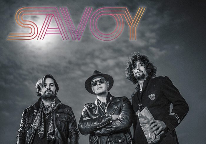 Three men posing under "SAVOY" logo.