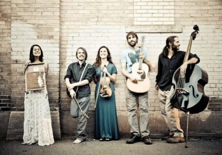 Band with instruments against a brick wall.
