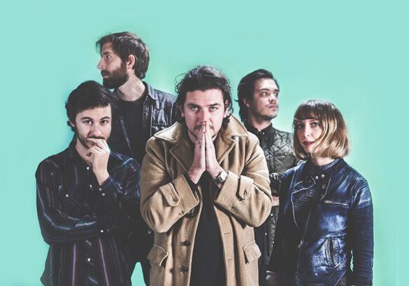 Five people posing against a turquoise background.