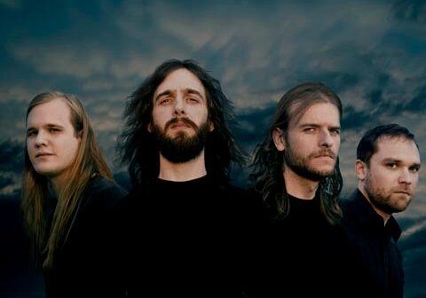 Four men standing under a cloudy sky.
