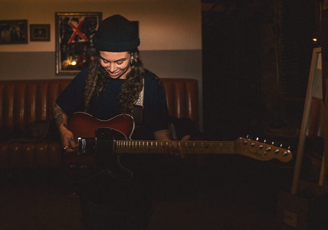 Person smiling while playing an electric guitar.