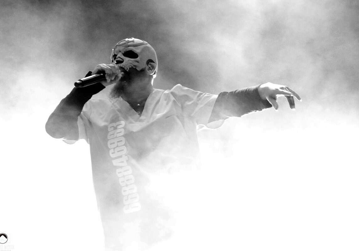 Singer in mask performing amidst smoke.