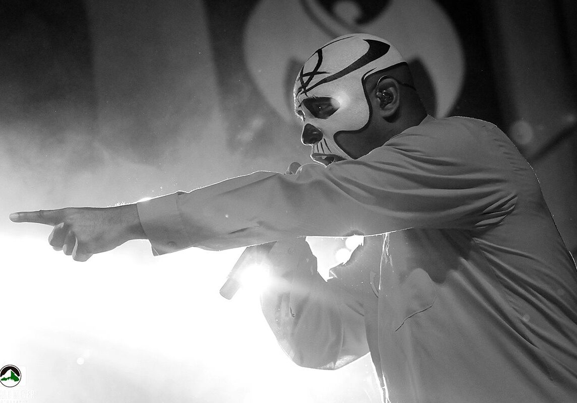 Masked performer pointing during a concert.