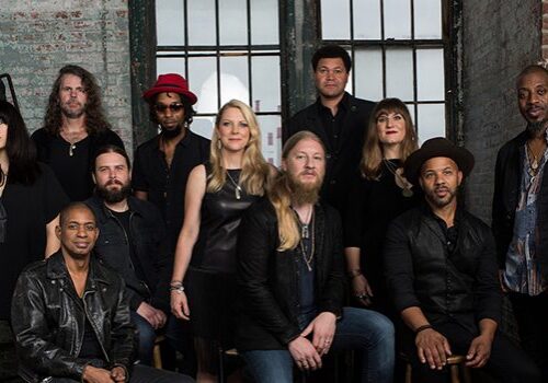 Group of musicians posing against brick wall.