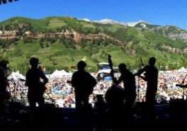 Silhouetted band performing at outdoor festival.