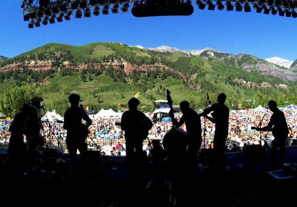 Silhouetted band performing at outdoor festival.