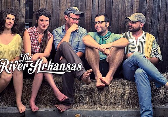Five people sitting on hay bales.