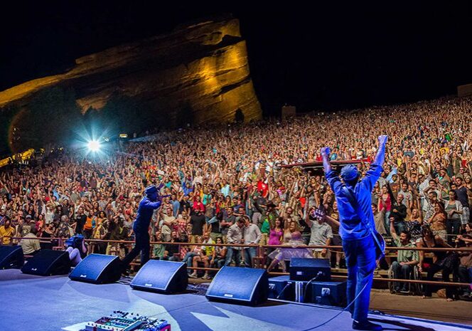 Concert crowd at outdoor amphitheater, night performance.