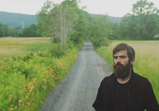Man standing on rural path through fields.