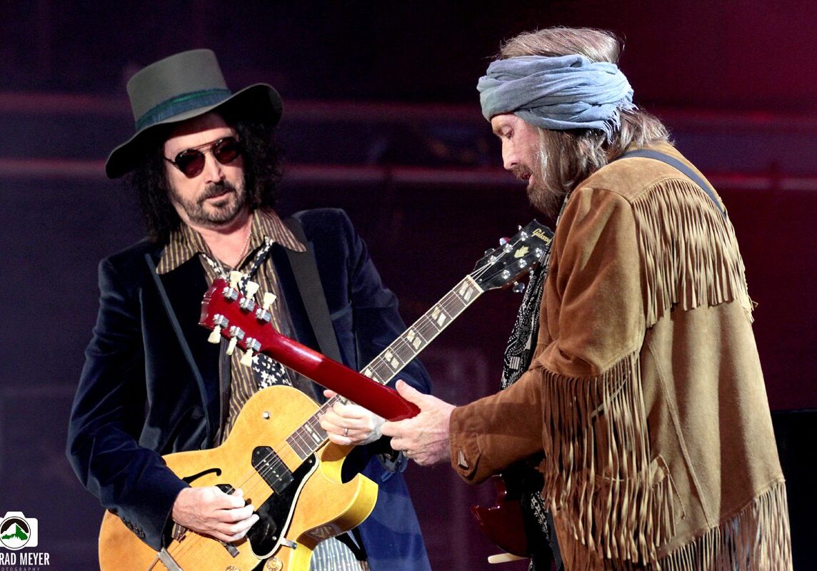 Two musicians playing guitars on stage.