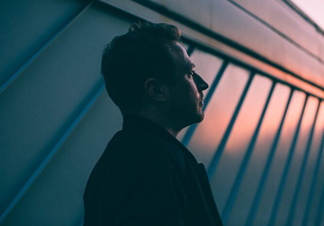 Man silhouetted against sunset, architectural background.