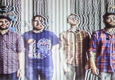 Distorted image of four men standing together.