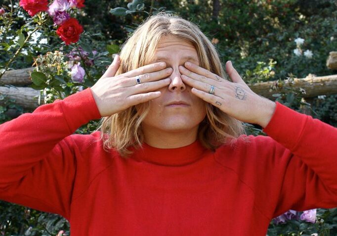 Person covering eyes in a garden.