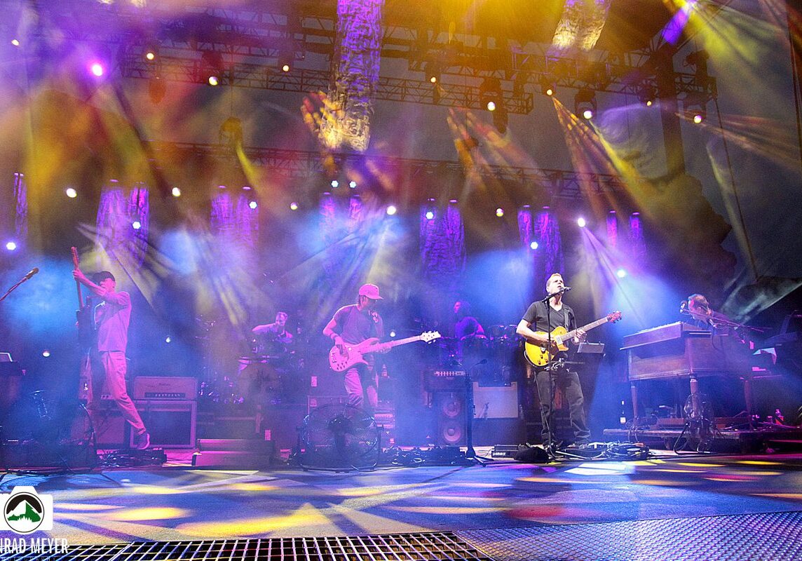 Band performing on stage with colorful lights.