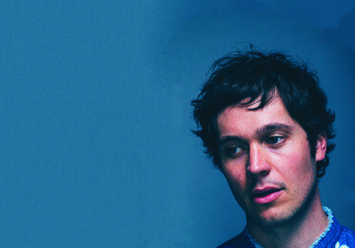 Man in blue tie-dye shirt, blue background.