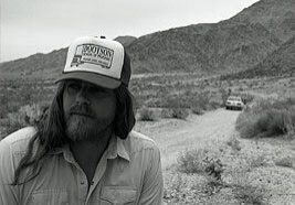 Man with cap in desert landscape.
