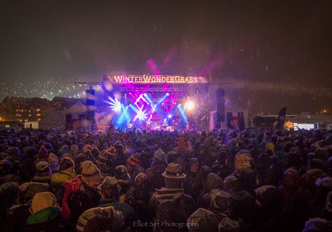 Outdoor concert with colorful stage lights.
