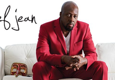 Man in red suit sitting on white couch.