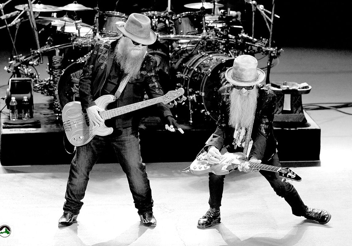 Two musicians performing with guitars on stage.